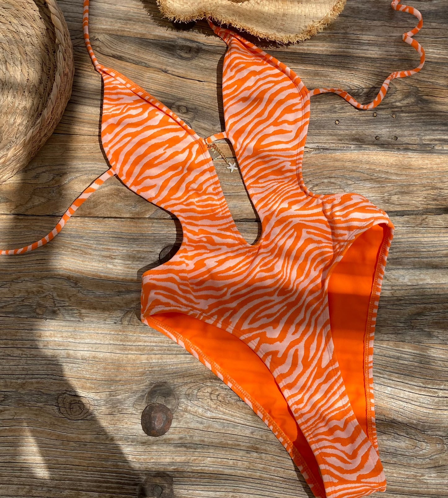 Amari Orange Zebra Plunge Push Up One Piece Swimsuit with High Cut leg with cut out features on gorgeous model - flat lay