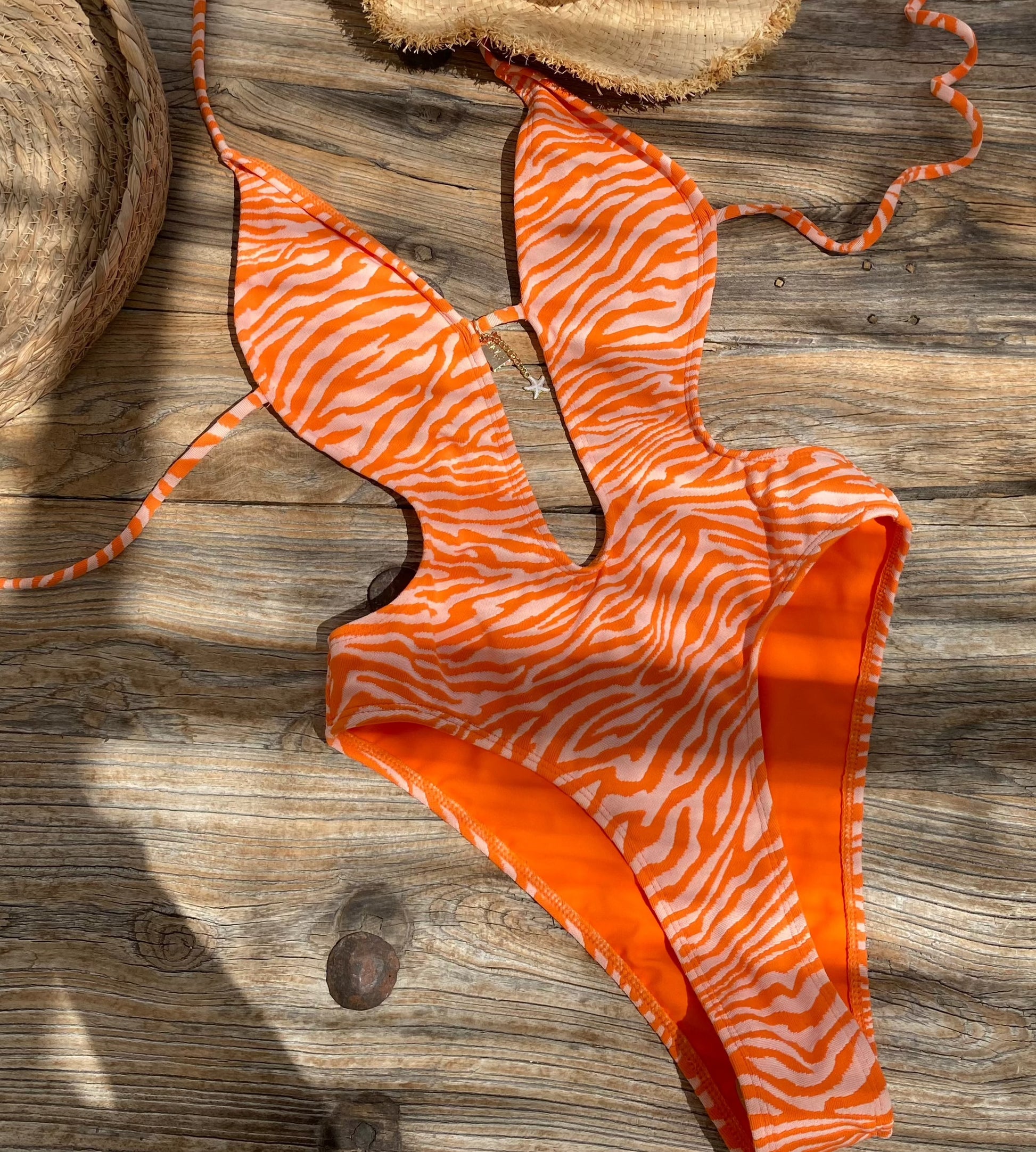 Amari Orange Zebra Plunge Push Up One Piece Swimsuit with High Cut leg with cut out features on gorgeous model - flat lay