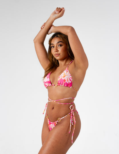 Beautiful vibrant pink printed bikini bottoms with tie side and gold o-ring detail on our model. Posed arms in the air