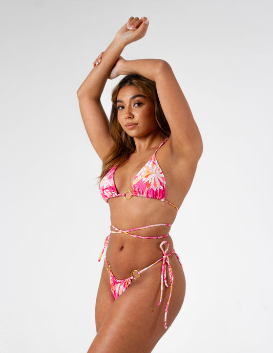 Beautiful vibrant pink printed triangle bikini top with adjustable ties and gold o-ring detail on our gorgeous model. Right side