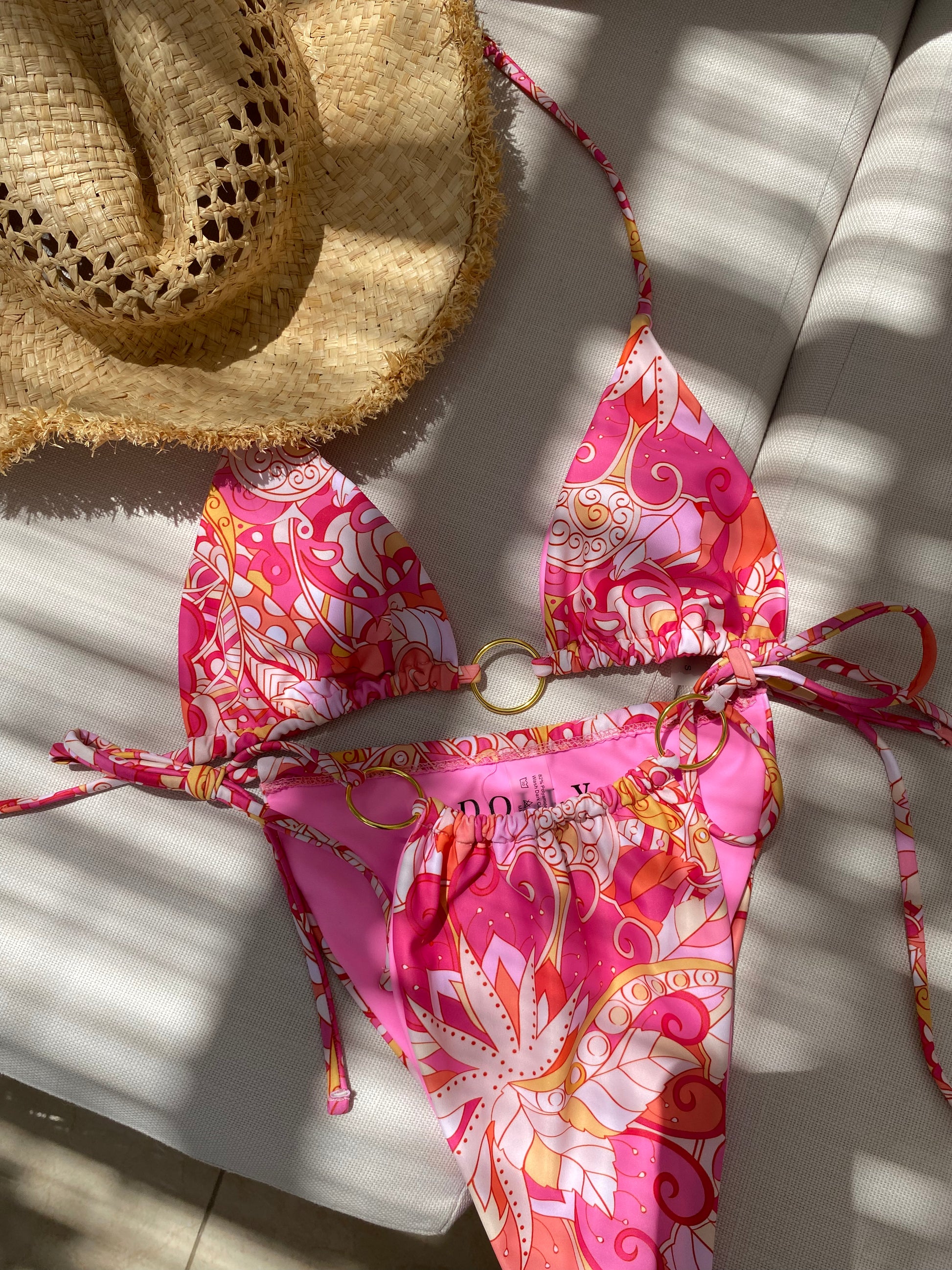 Beautiful vibrant pink printed triangle bikini top with adjustable ties and gold o-ring detail on our gorgeous model. Flat lay