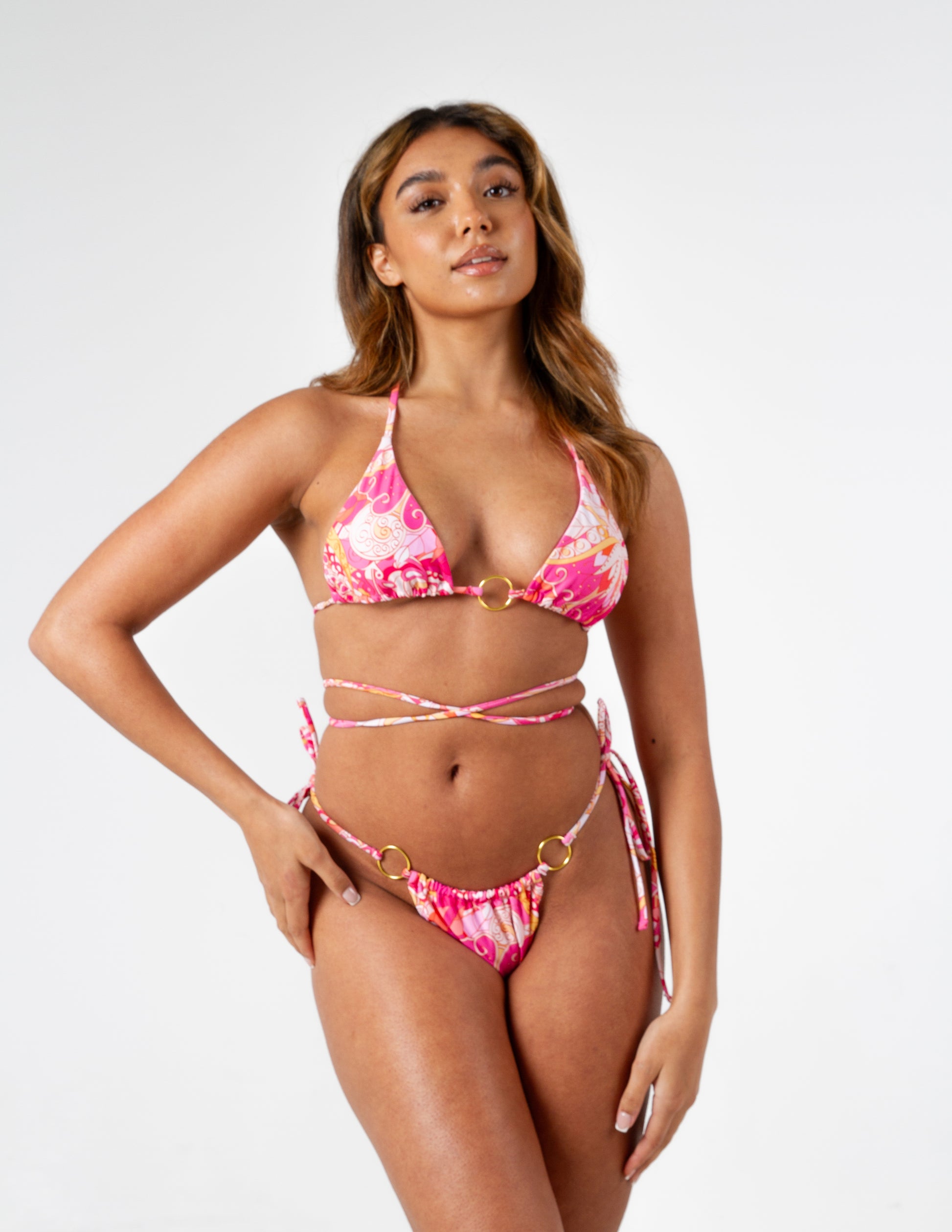 Beautiful vibrant pink printed triangle bikini top with adjustable ties and gold o-ring detail on our gorgeous model. Front